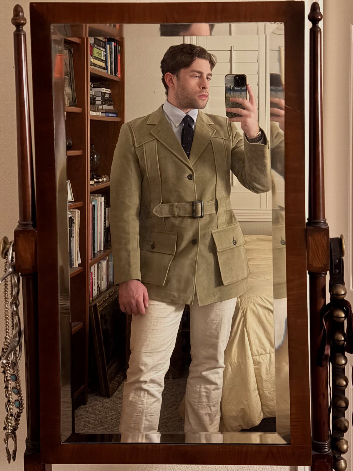 Man wearing an olive green belted Norfolk jacket and cream trousers in a mirror selfie.