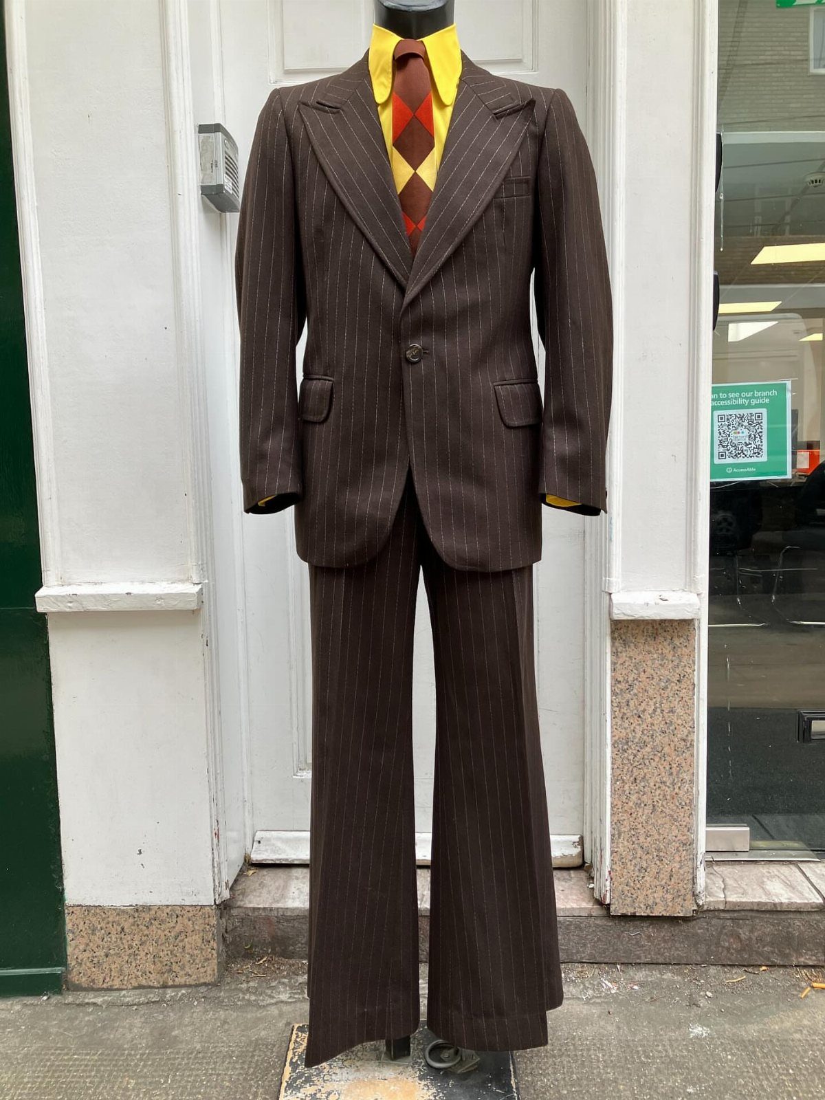 Brown pinstripe suit with wide lapels and flared trousers on a mannequin.