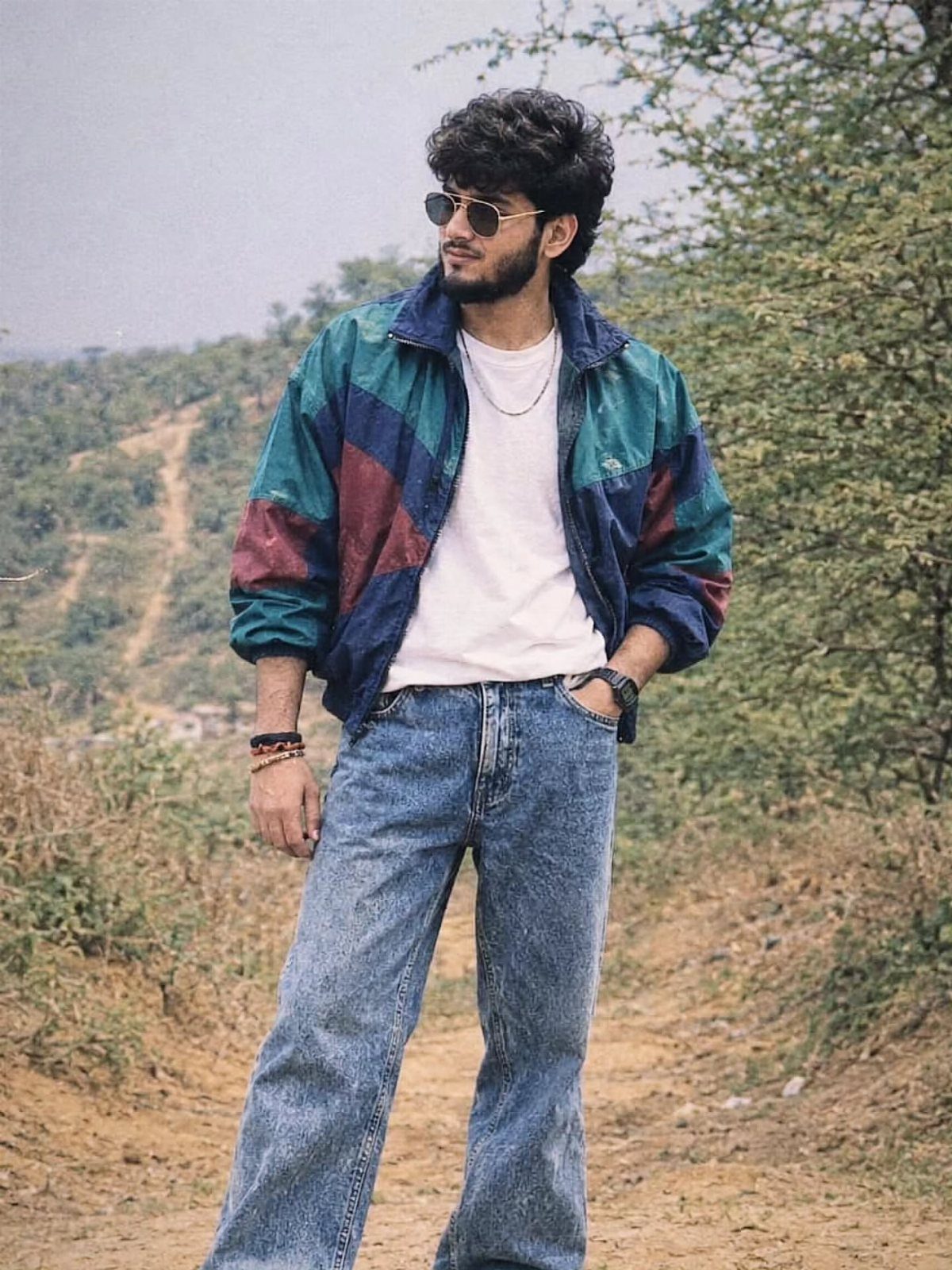 Man wearing a vintage color-blocked windbreaker and wide-leg blue jeans outdoors.