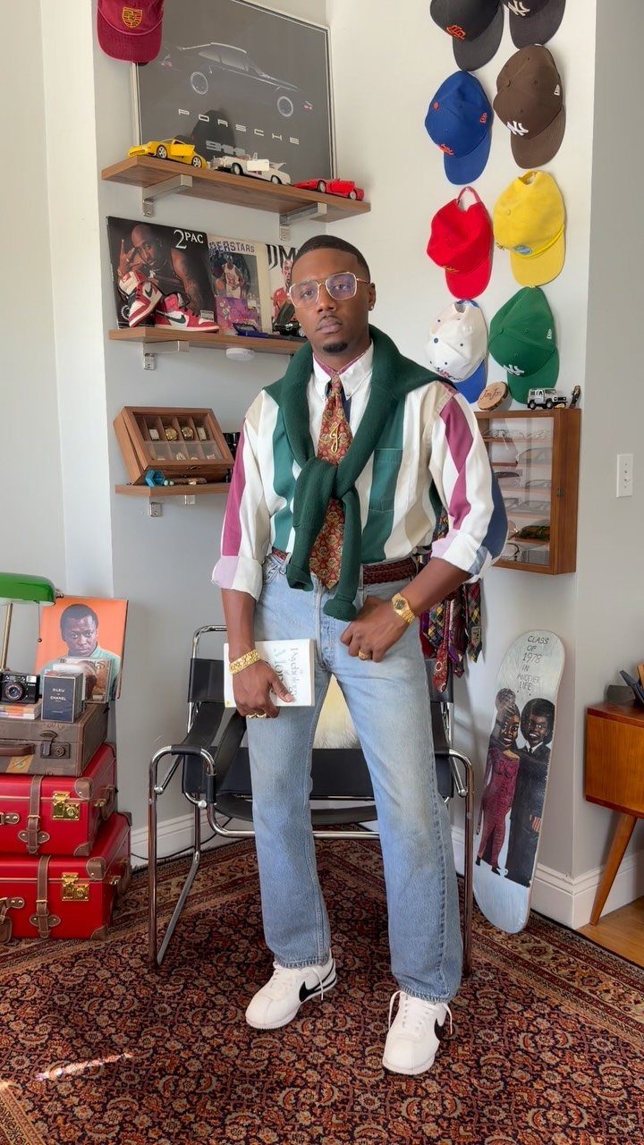 Man in 1980s style button-down shirt, tie, and sweater draped over shoulders.