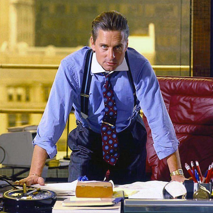 Man in 1980s office attire wearing a blue shirt, patterned tie, and suspenders.