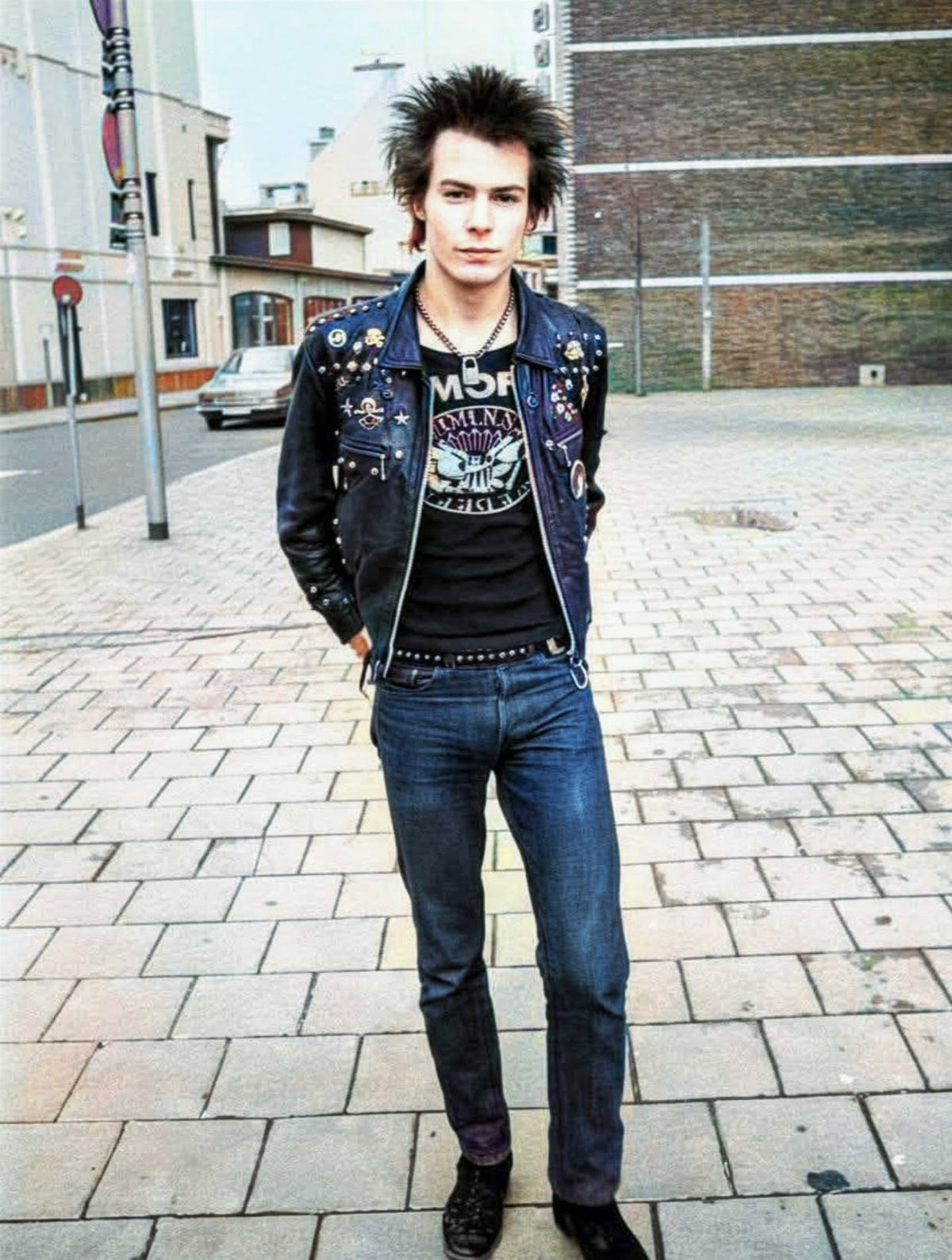 Man with spiky hair wearing a studded leather jacket and graphic t-shirt.