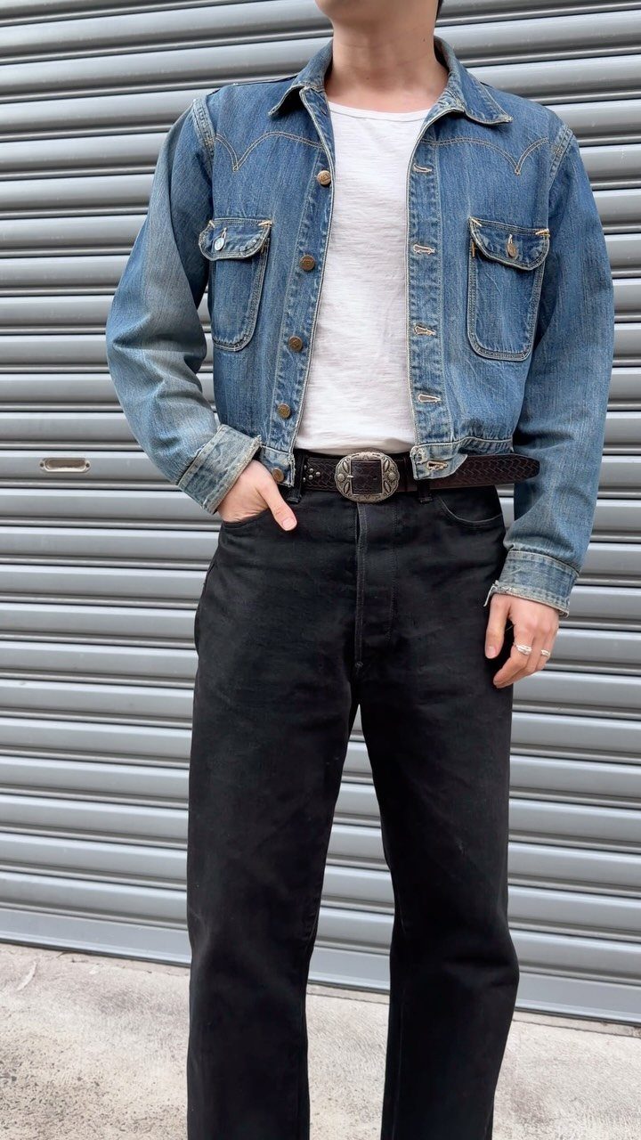 Person wearing a blue denim jacket, white t-shirt, and black high-waisted jeans.