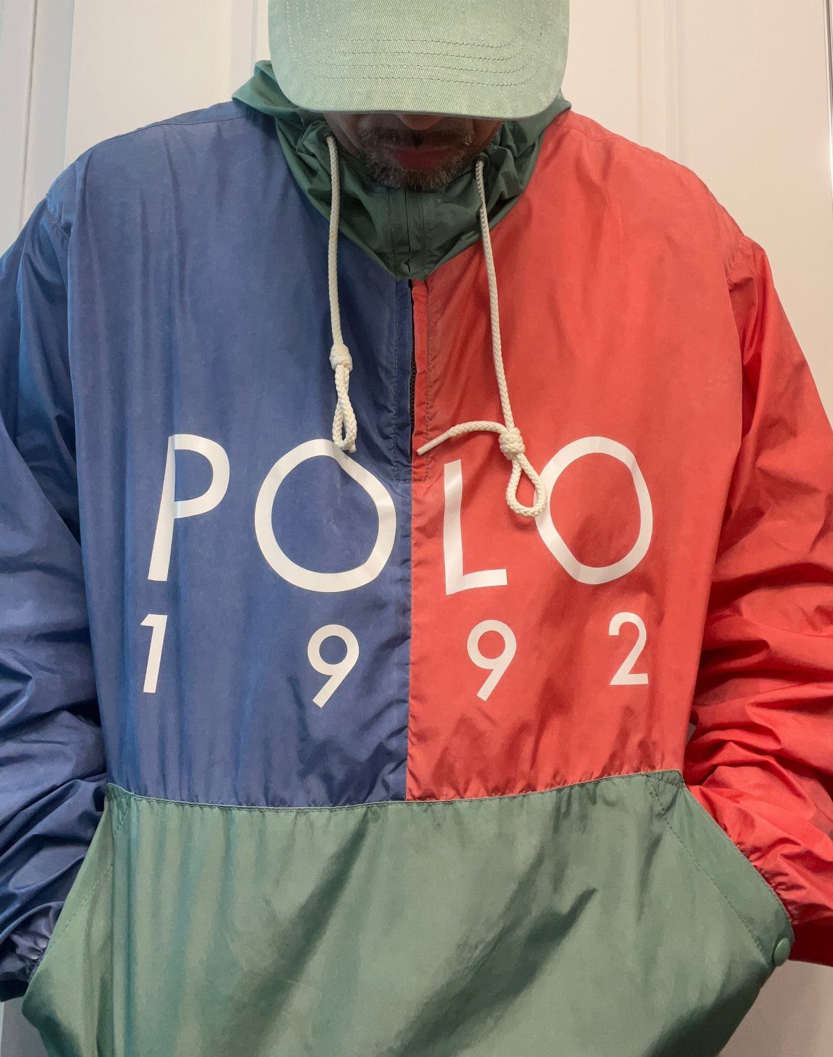 Person wearing a color-blocked Polo 1992 windbreaker and a light green bucket hat.