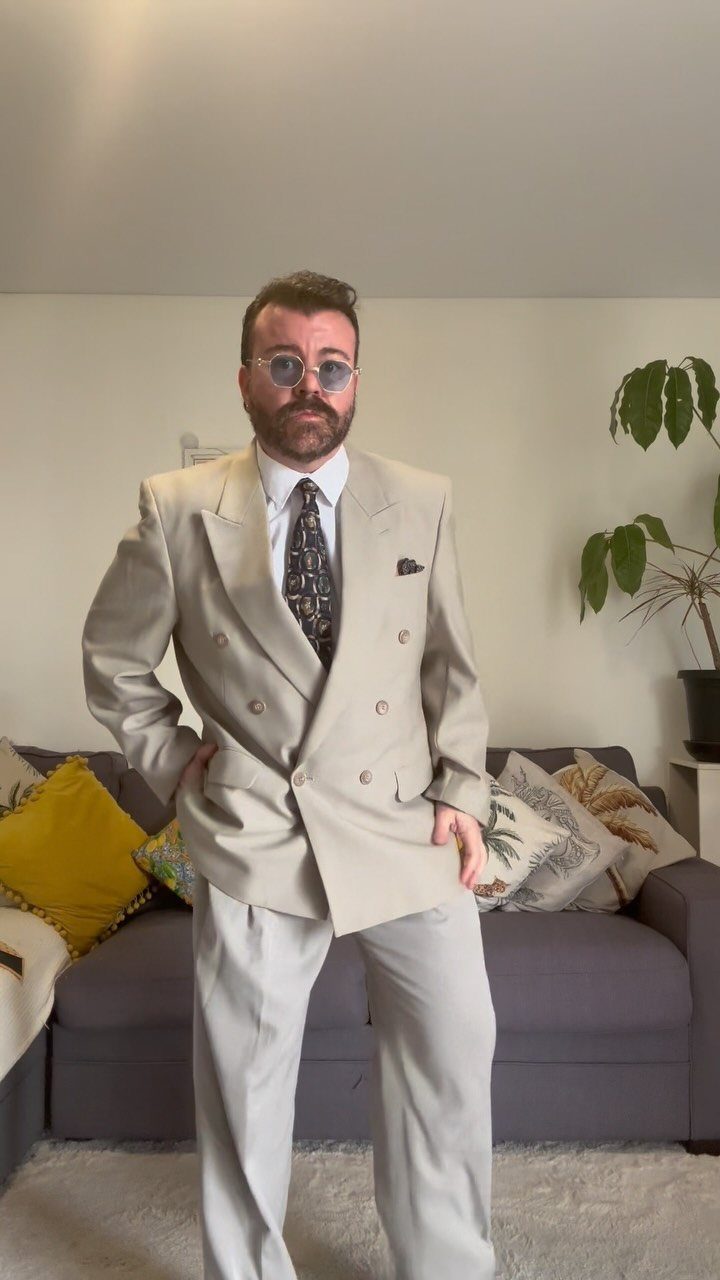 Man wearing an oversized beige double-breasted suit jacket and a wide patterned tie.