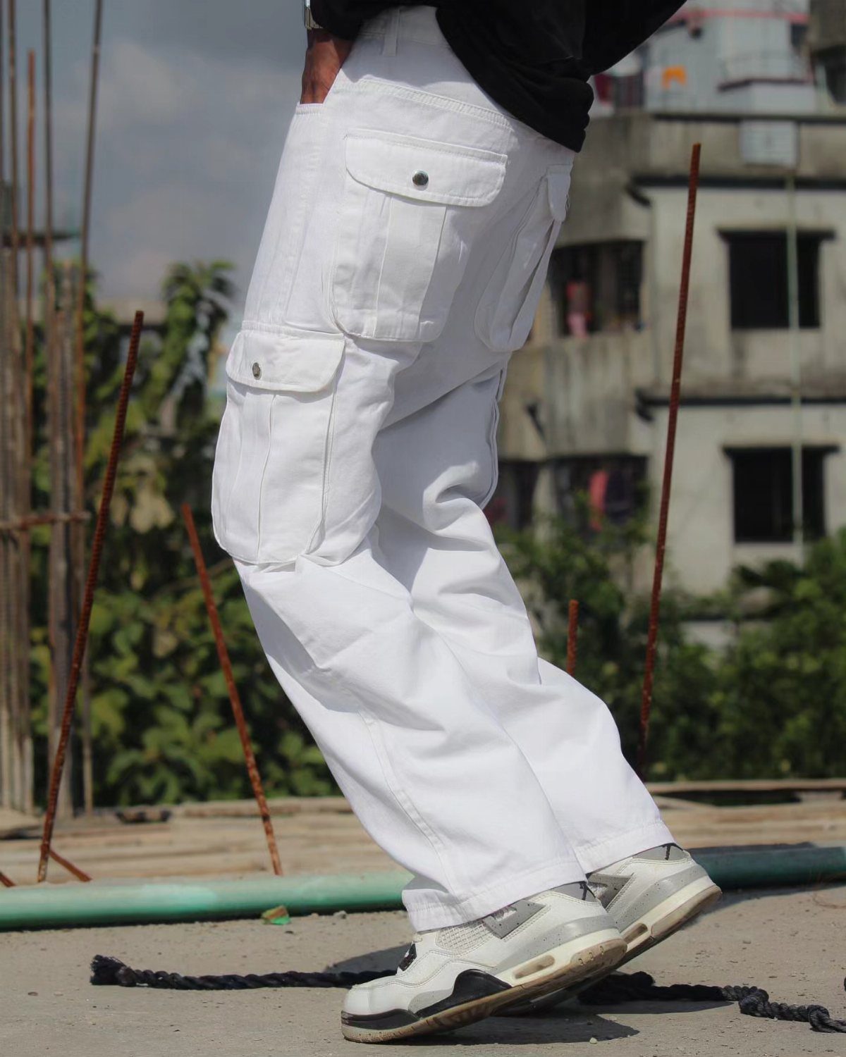 White cargo pants with multiple pockets and white sneakers on a person.