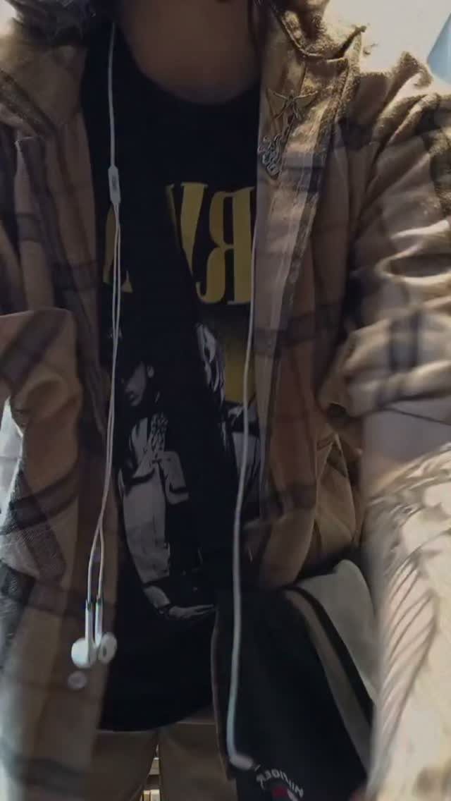 Person wearing a brown plaid flannel shirt over a black graphic t-shirt.