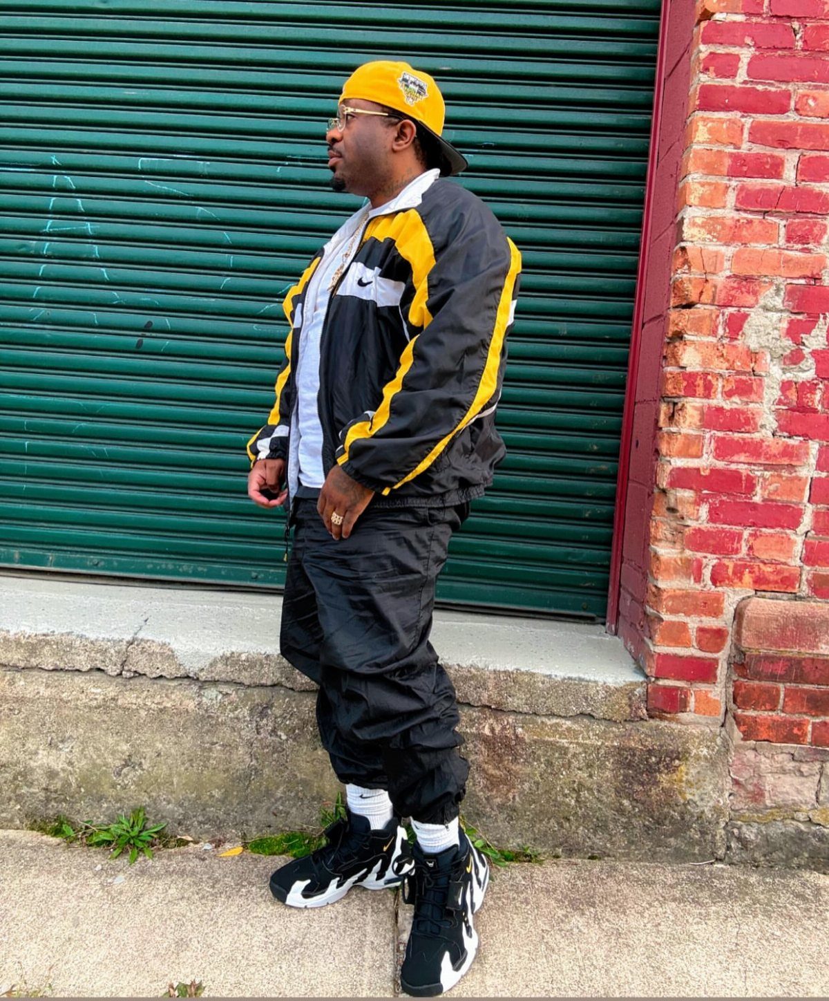 Man in 90s streetwear wearing chunky black and white sneakers and a windbreaker.
