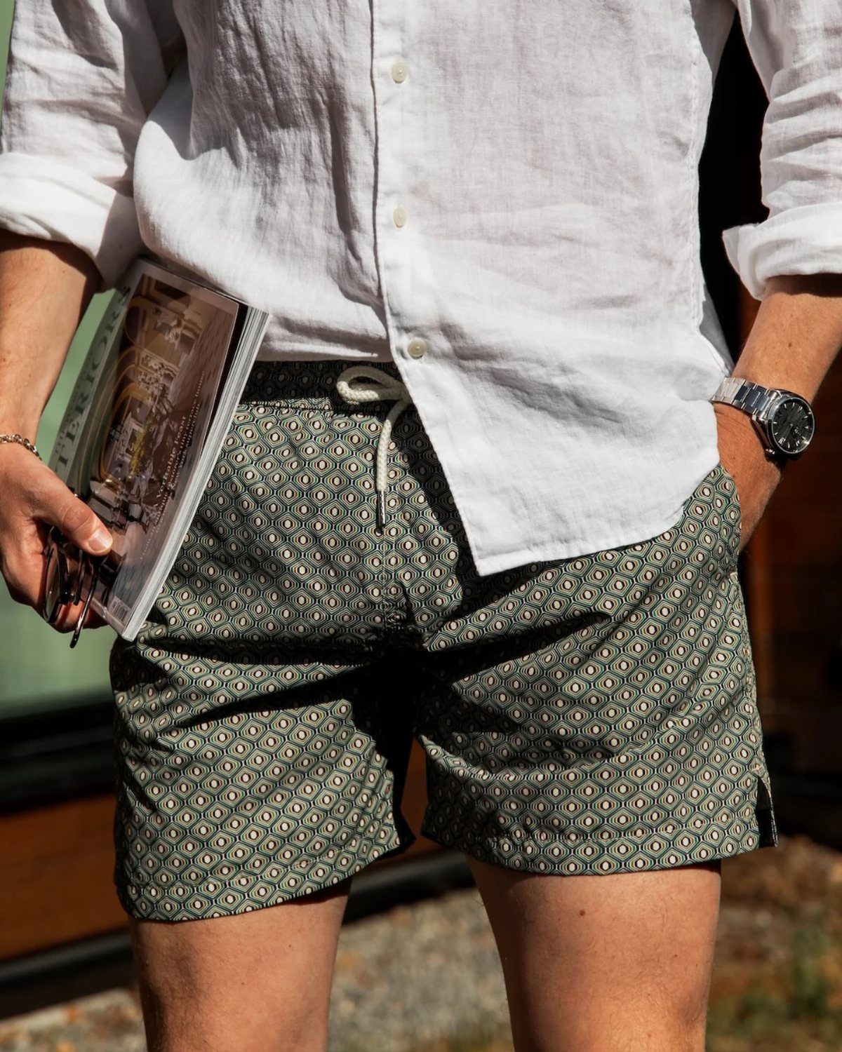 Man wearing green patterned casual shorts and a white linen shirt.