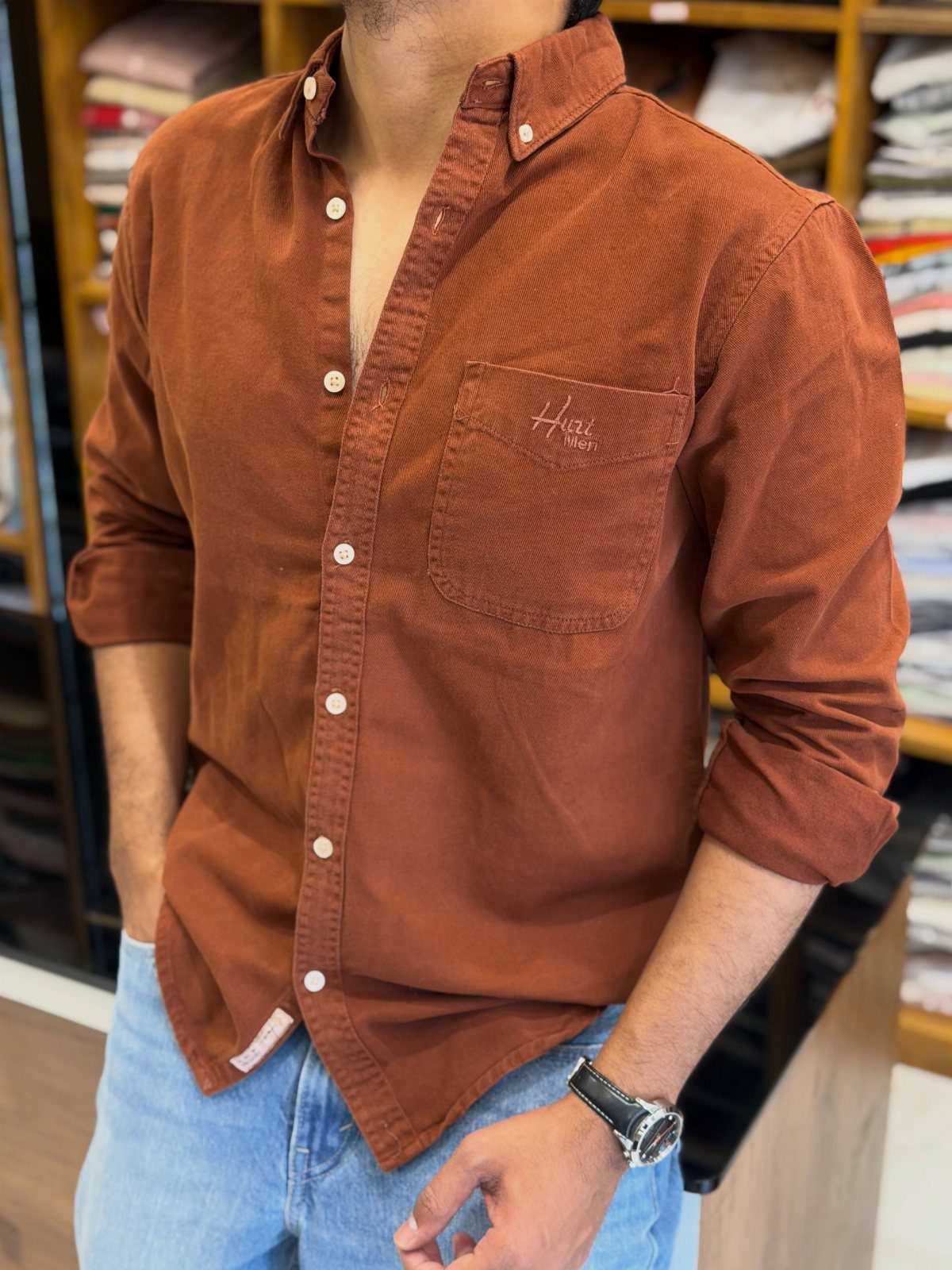 Man wearing a rust-colored corduroy button-down shirt and light blue denim jeans.