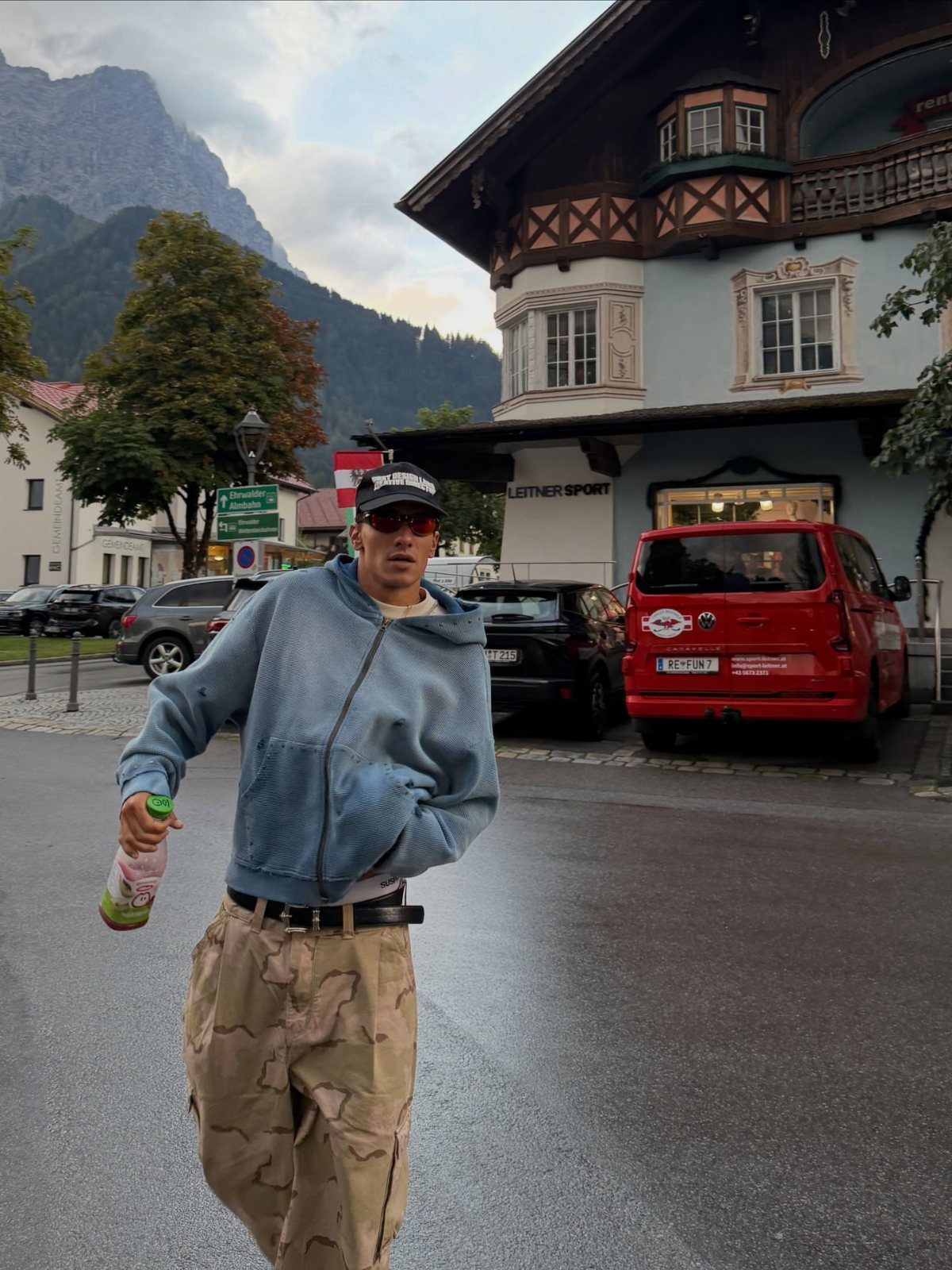 Man in blue fleece jacket and tan cargo pants standing in mountain village
