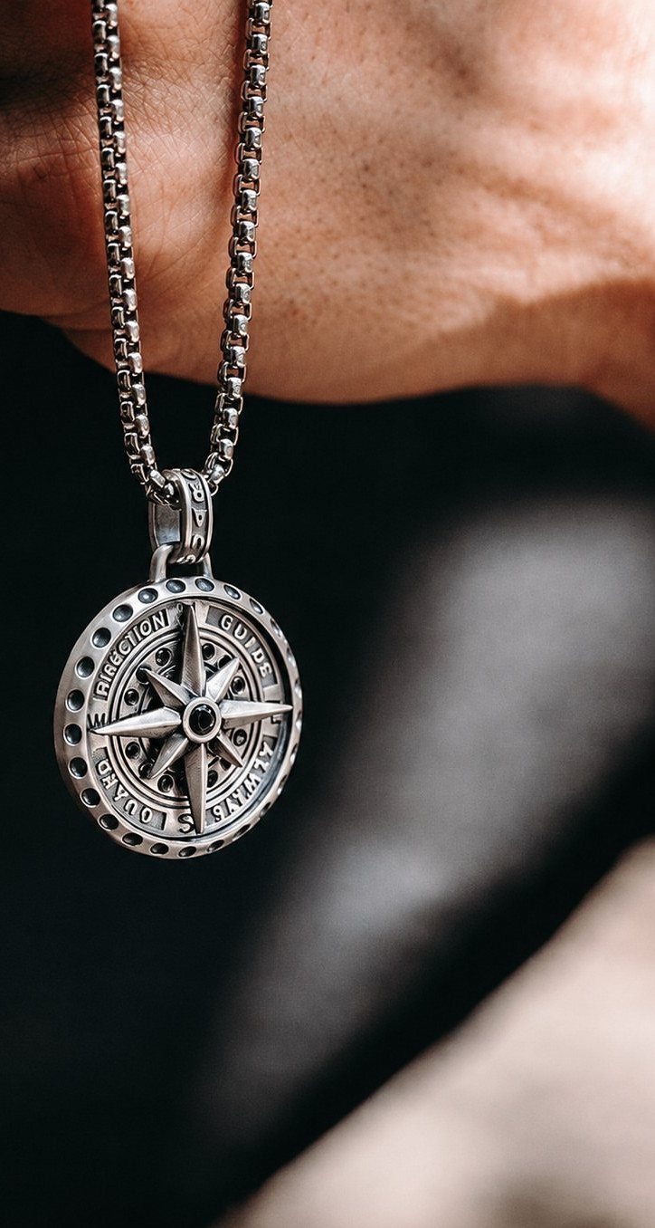 Silver box chain necklace with a detailed circular compass pendant on a person.