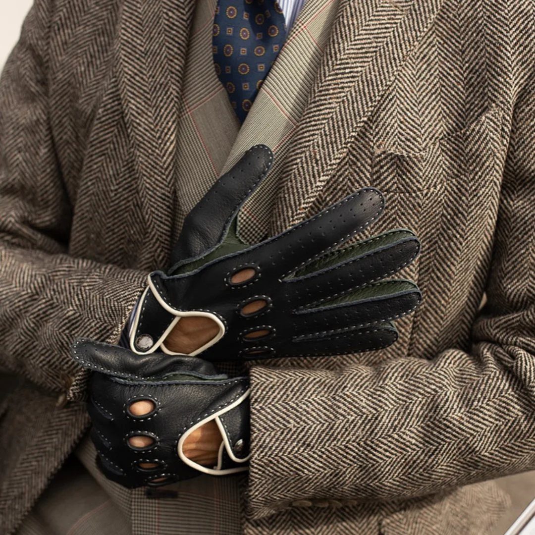 Black leather driving gloves with white trim worn with a brown tweed blazer.