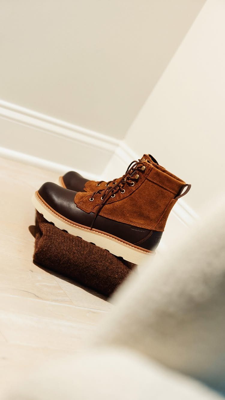Brown leather and suede winter boots resting on a dark brown folded cloth.