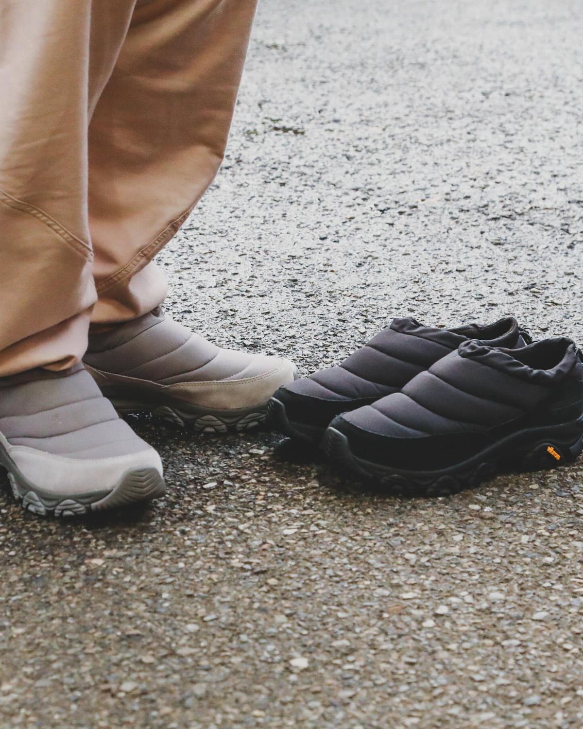 Grey and black puffer winter boots on a grey asphalt ground.