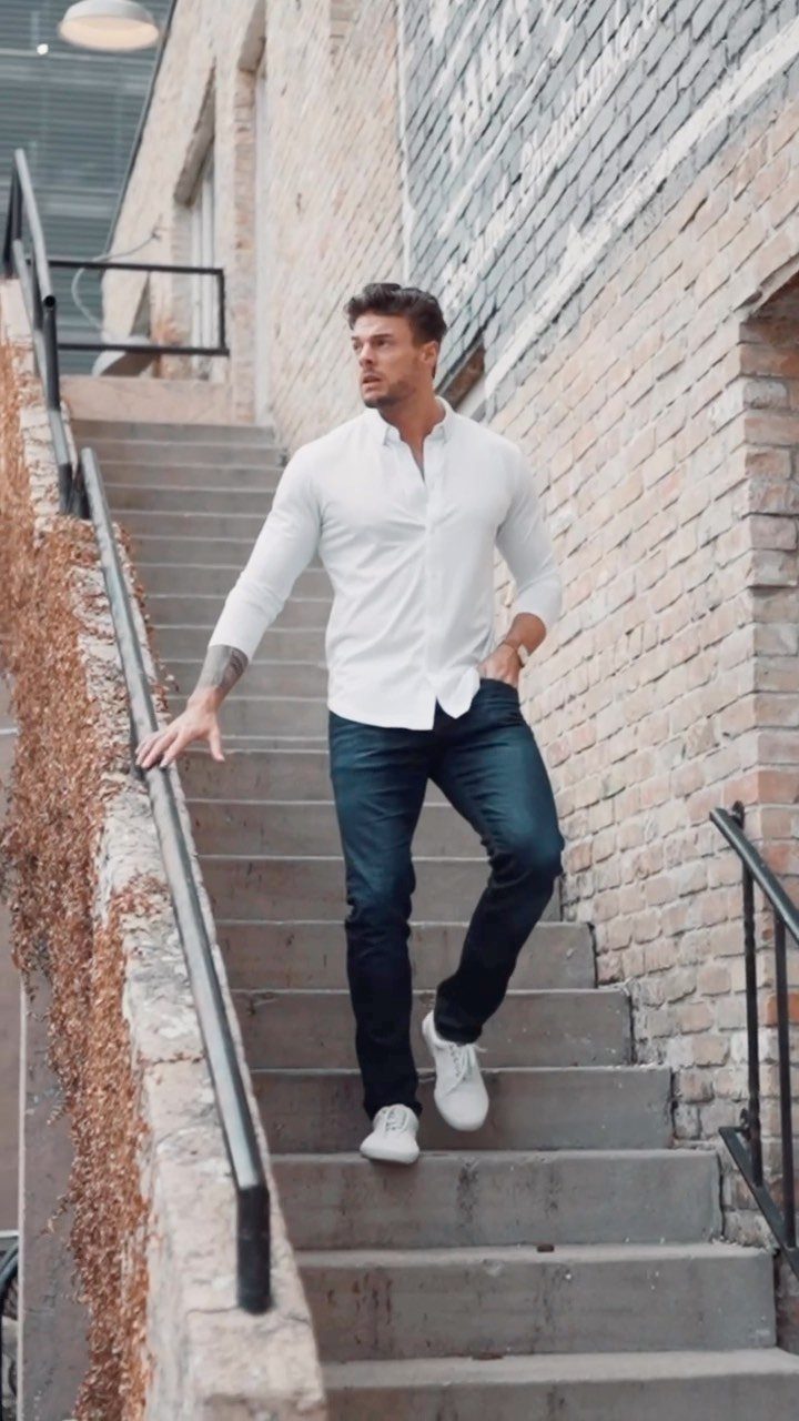 Man in white button-down shirt and navy trousers walking down concrete stairs.