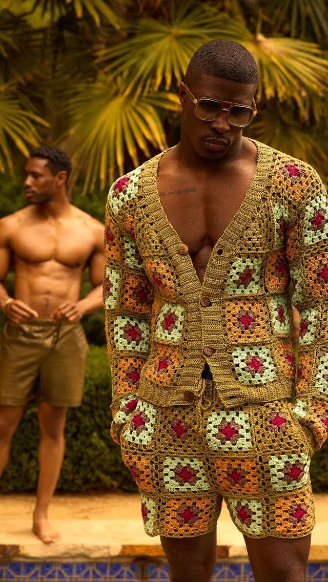 Man wearing a colorful crochet granny square cardigan and matching shorts in tropical setting