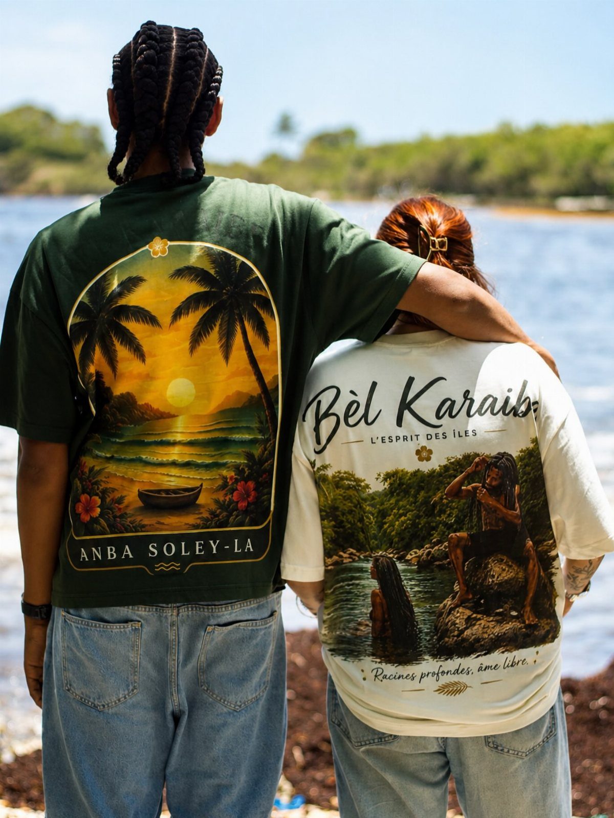 Two people wearing oversized graphic souvenir t-shirts with tropical beach prints by the water.