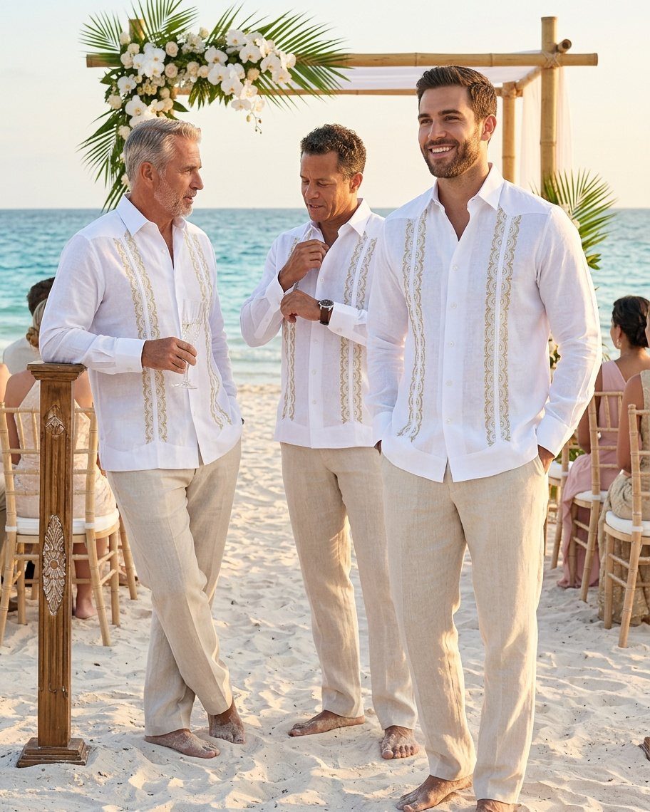 Three men wearing white embroidered guayabera shirts and beige linen pants on a beach.