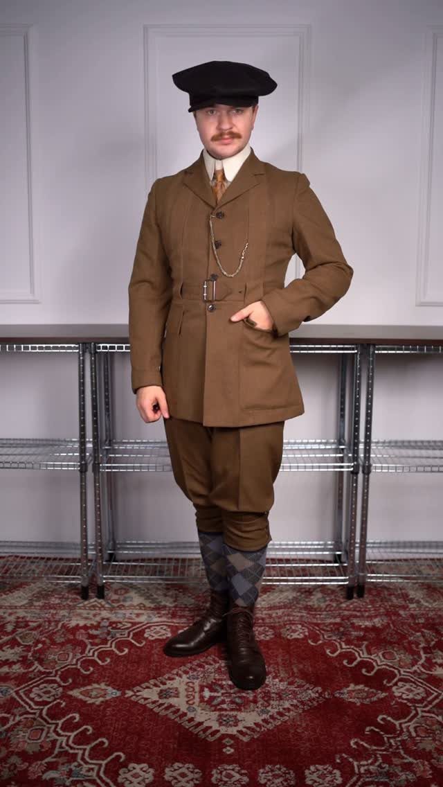 Man in a brown Norfolk jacket and knickerbockers wearing a black flat cap.