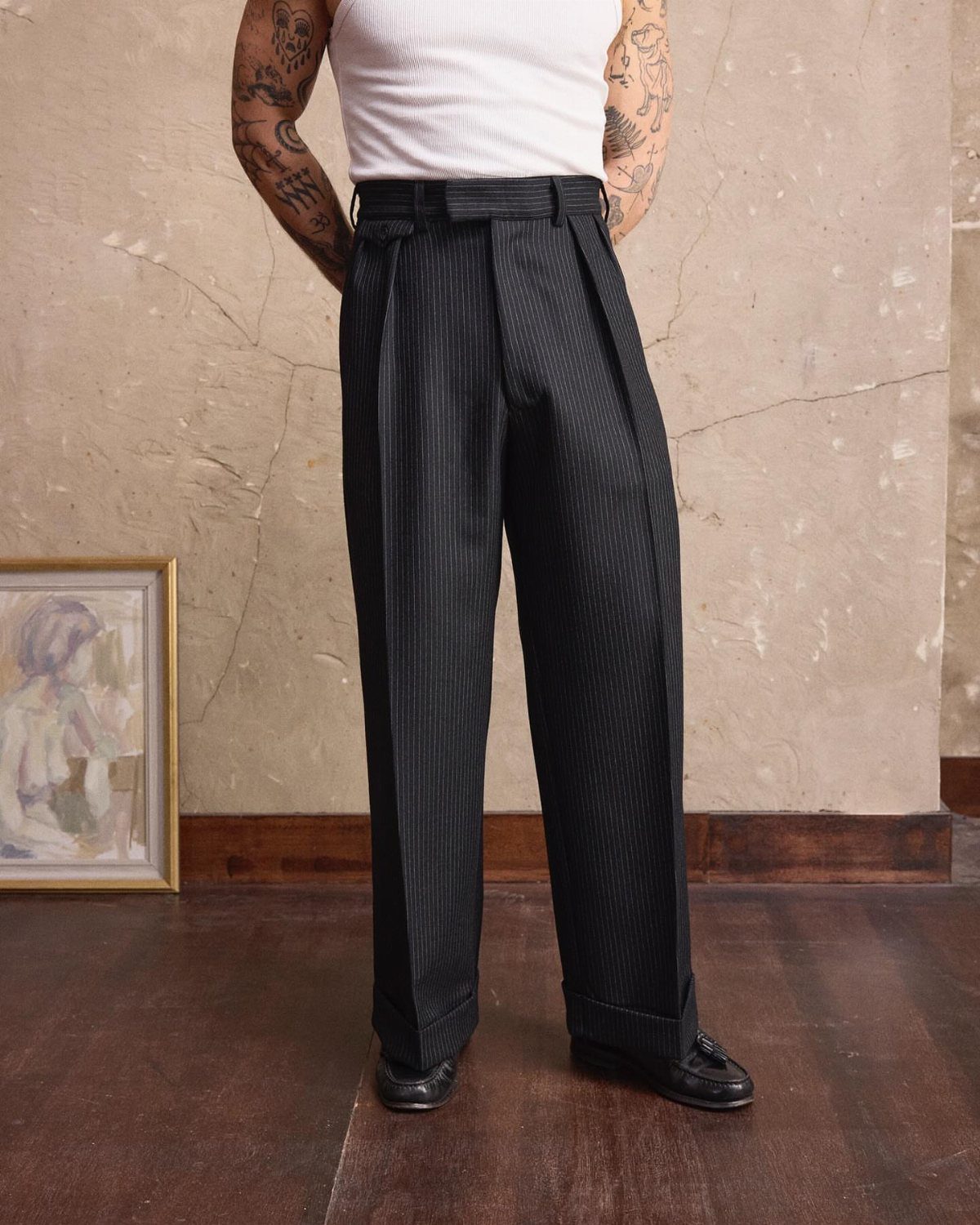 High-waisted charcoal pinstripe trousers with cuffs and a white tank top.