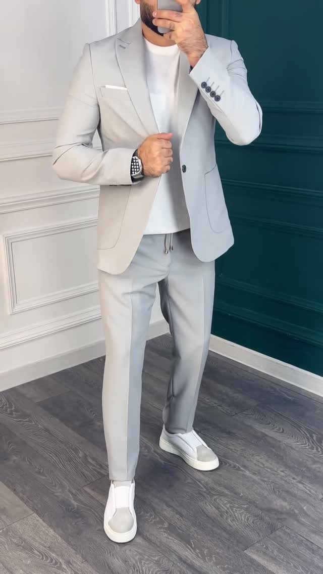 Man in a light grey suit with a white t-shirt and white sneakers.