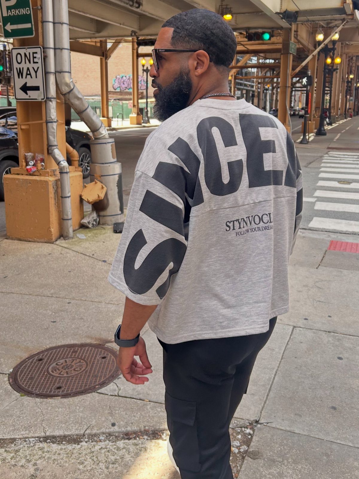 Man in oversized grey graphic t-shirt and black cargo pants on Chicago street.