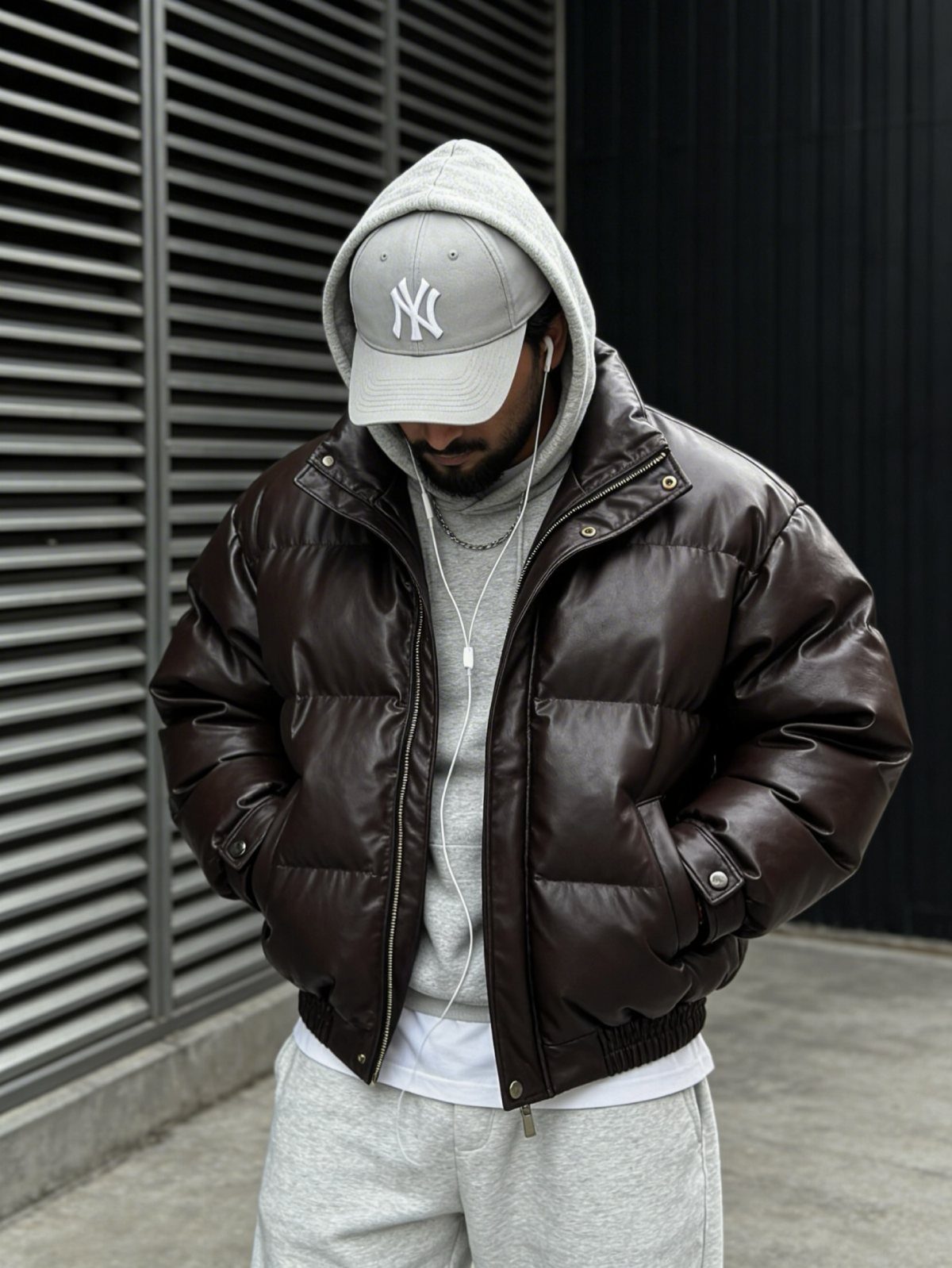 Man in brown puffer jacket, grey hoodie, sweatpants, and white baseball cap.