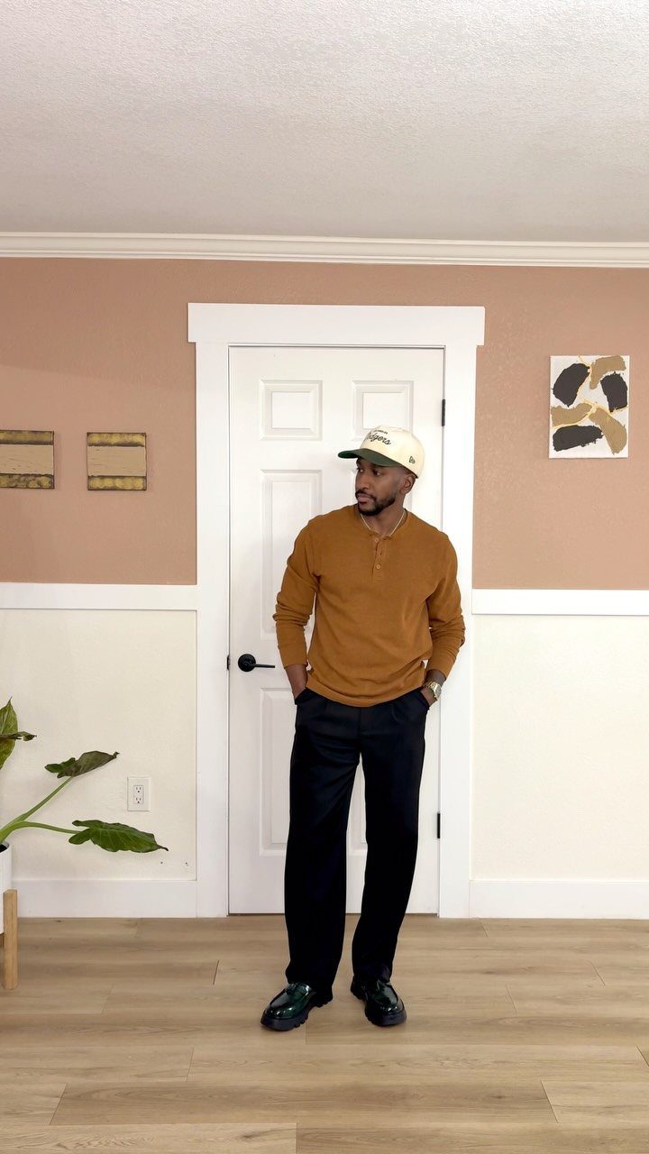 Man wearing a mustard-yellow long-sleeved shirt and black trousers in a home setting.