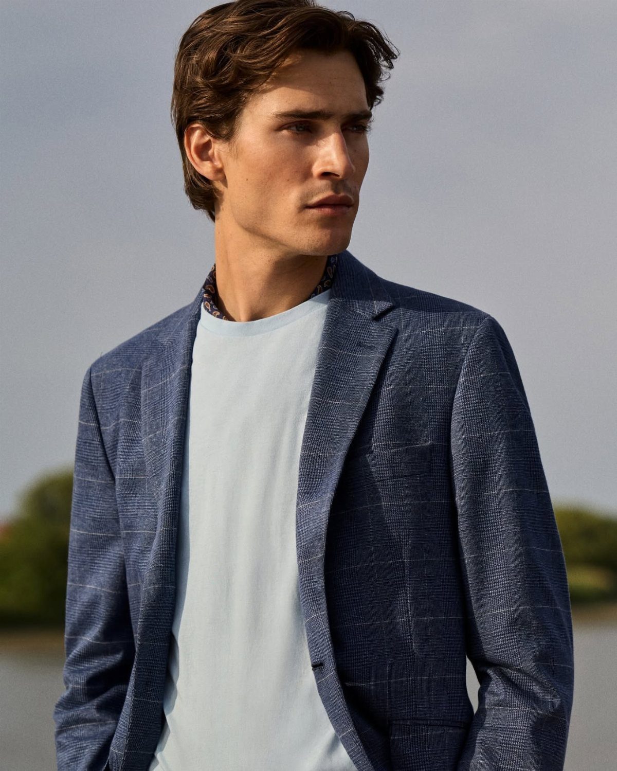Man wearing a blue textured blazer and light blue t-shirt outdoors.