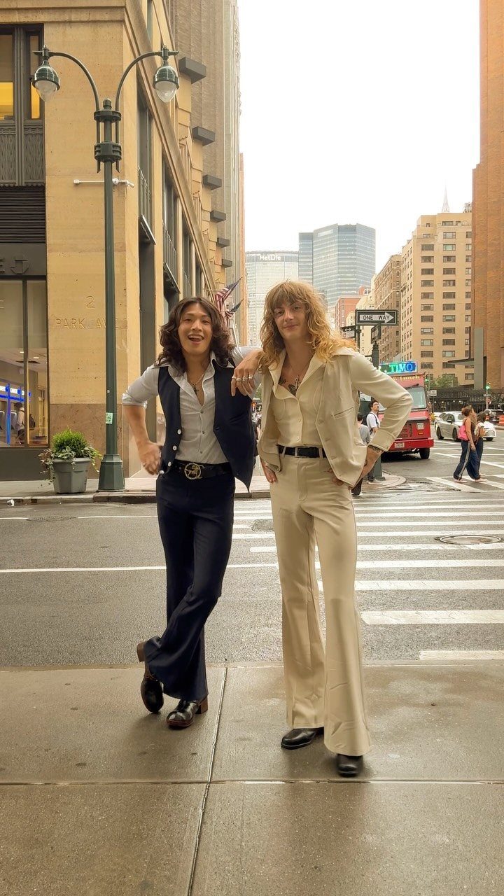 10 Images of 70's Men's Fashion from Flares to Fur Coats 3 Two people wearing 1970s style flared trousers and button-down shirts on a city street