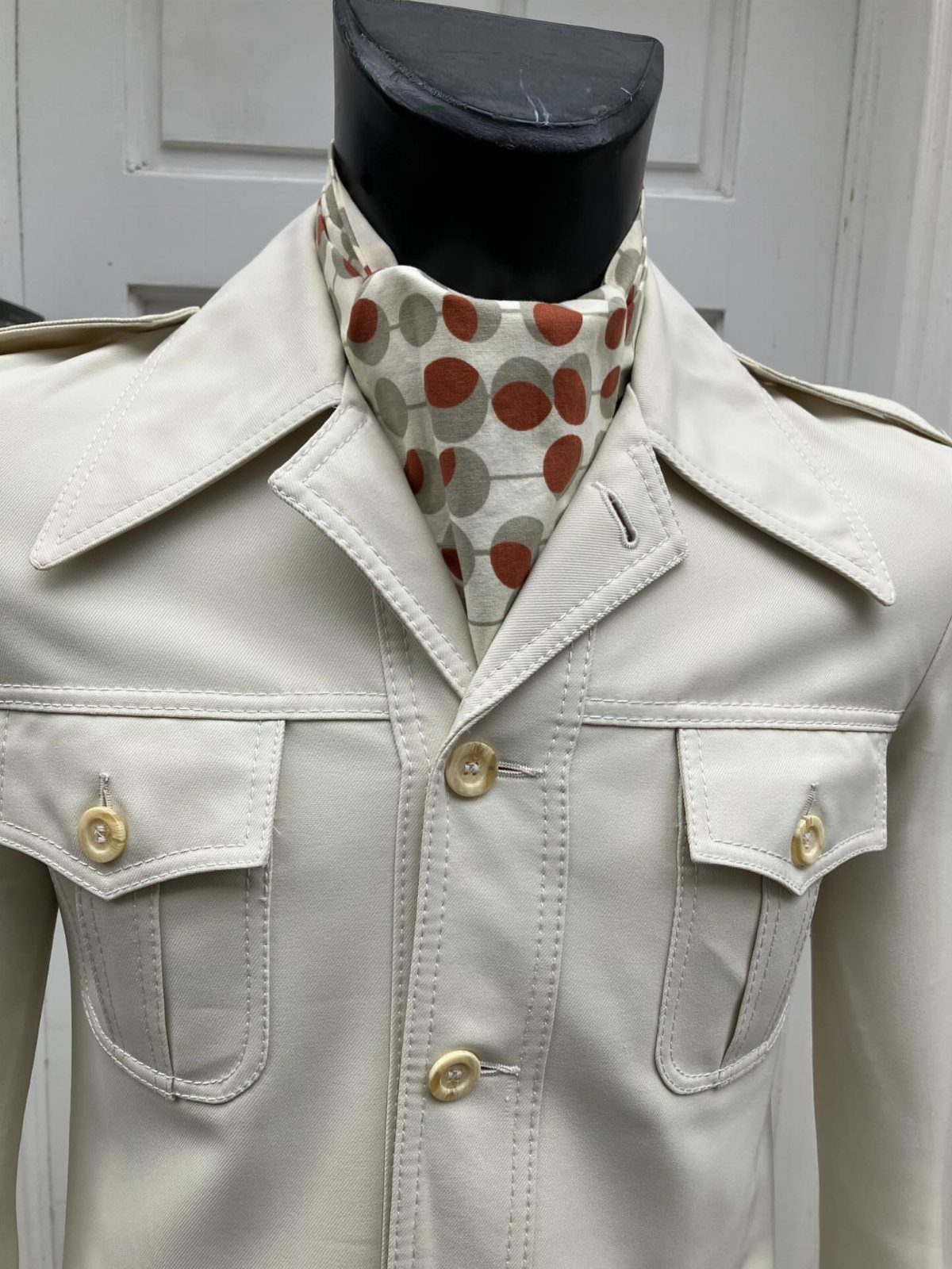 10 Images of 70's Men's Fashion from Flares to Fur Coats 8 Cream vintage jacket with wide collars and a brown polka-dot cravat on a mannequin.