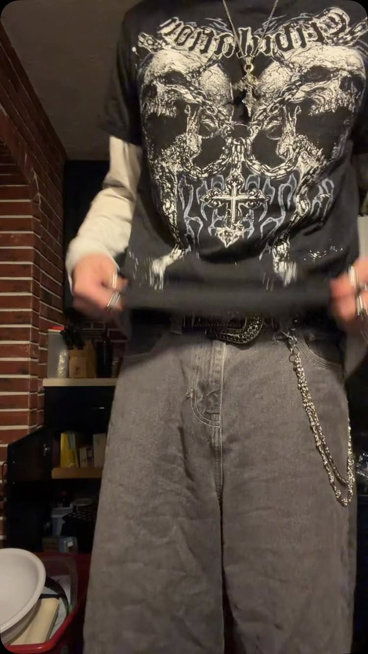 Person wearing a black skull graphic tee and wide-leg grey denim trousers.