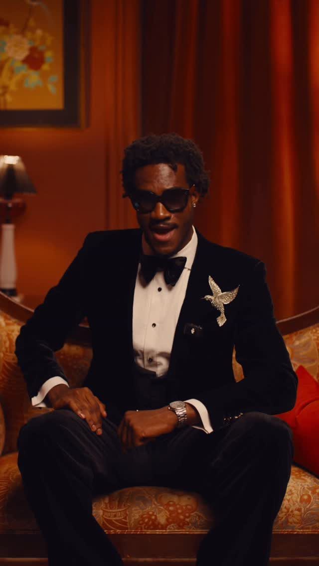 Man in black velvet tuxedo with sunglasses, bow tie, and silver bird lapel brooch.