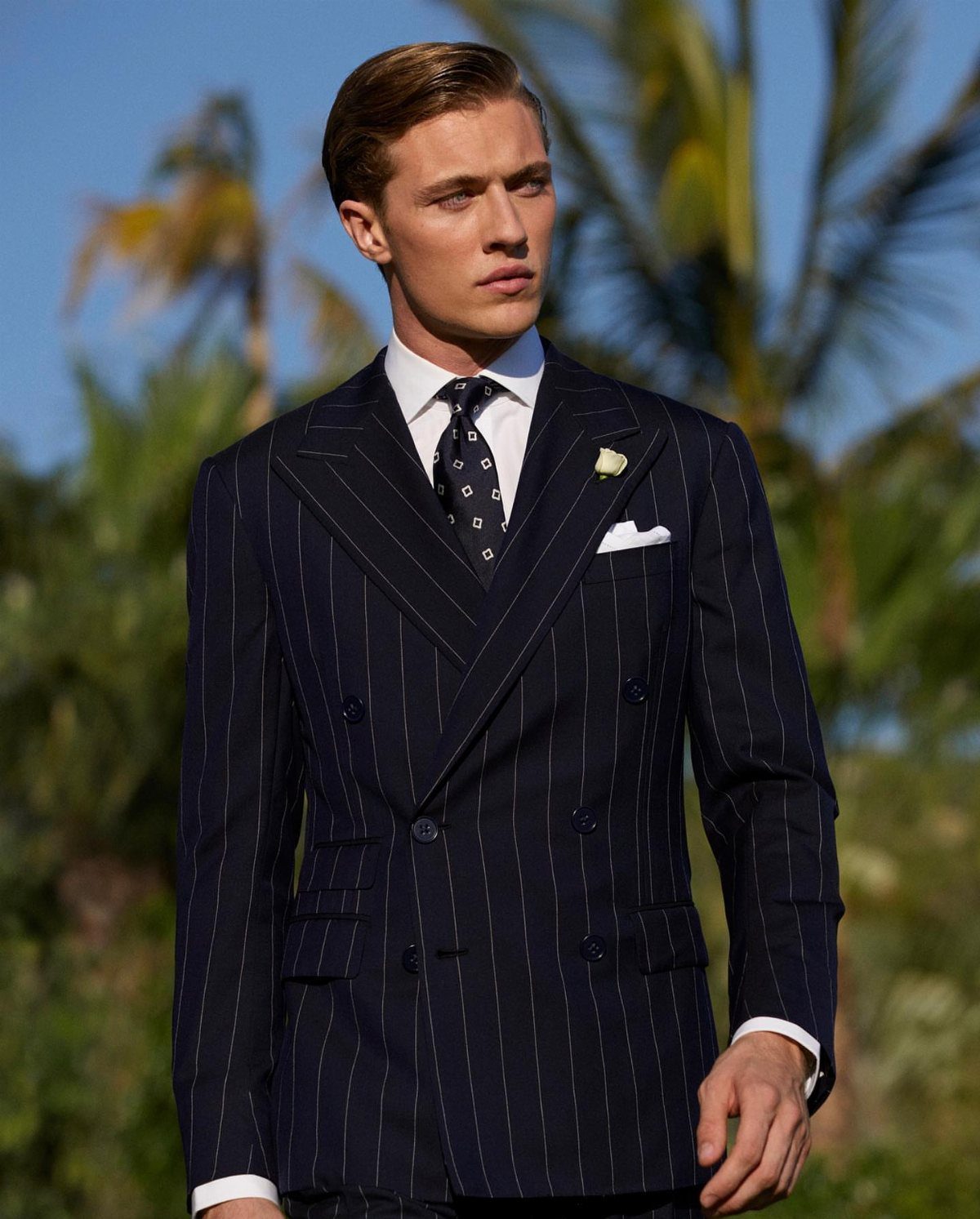 Man in a navy blue double-breasted pinstripe suit with a white pocket square.