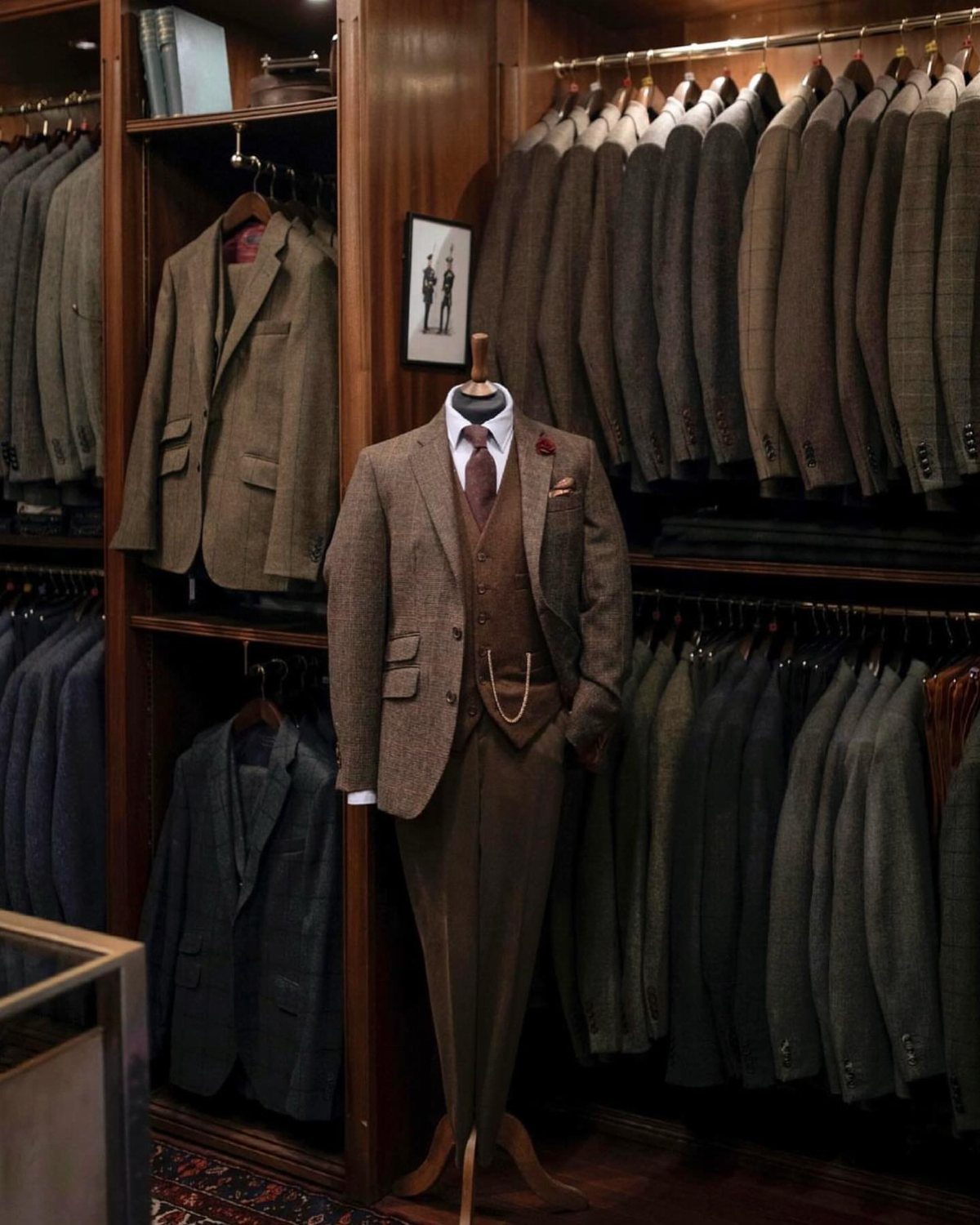 Brown three-piece tweed suit on a mannequin inside a luxury wooden wardrobe.