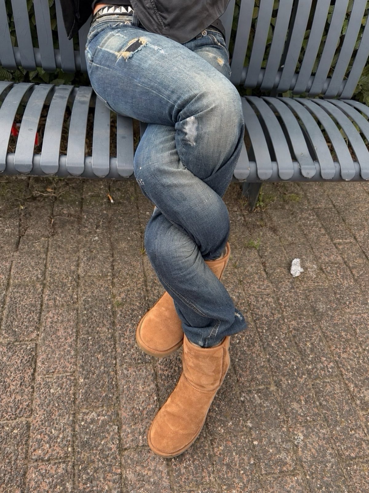 Tan suede Ugg boots paired with blue distressed denim jeans on a person.