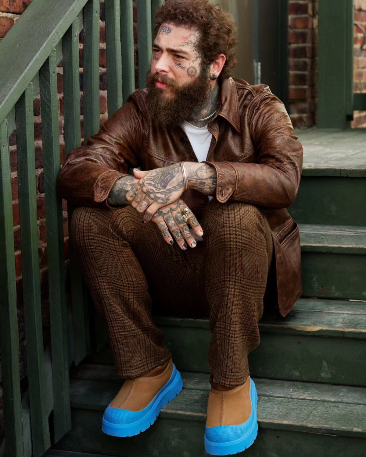Man in brown leather jacket and plaid pants wearing tan Ugg boots with blue soles.