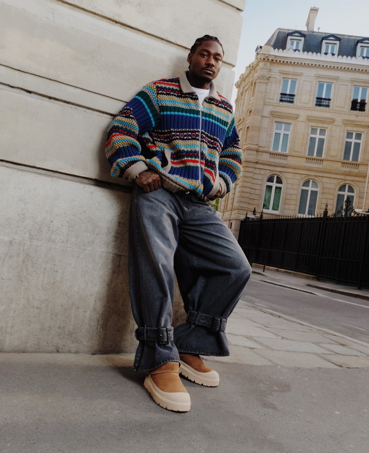 Man wearing a colorful striped cardigan, wide grey jeans, and tan Ugg boots.