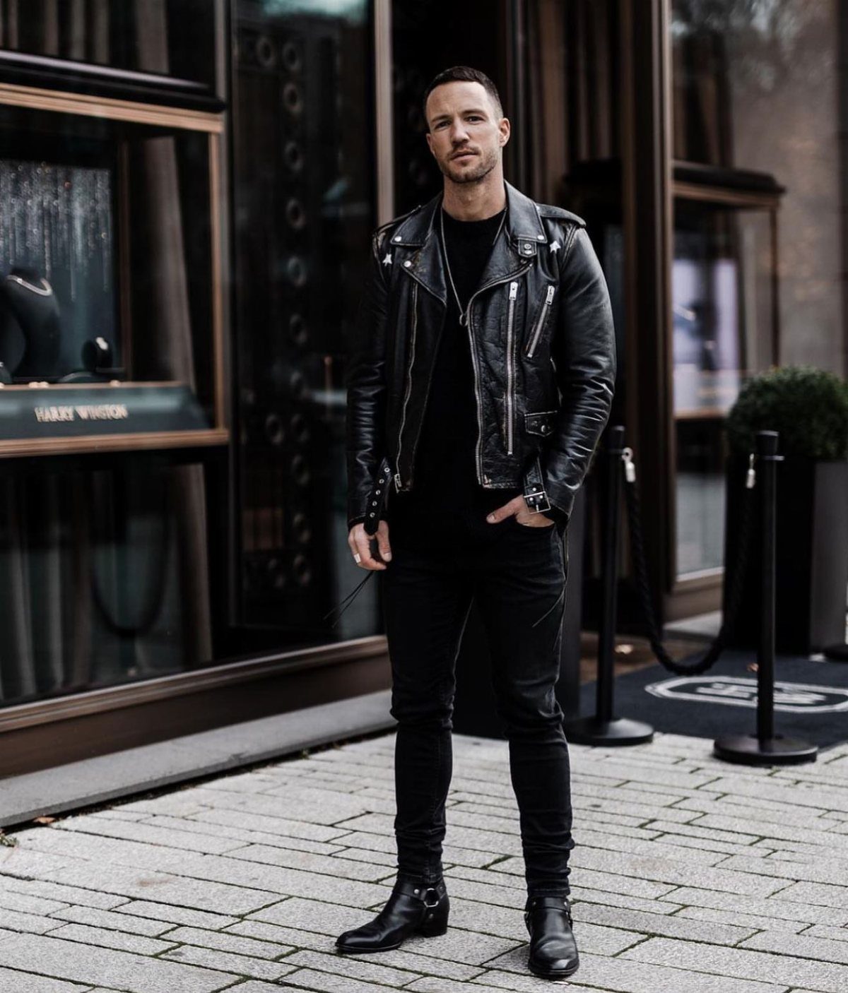 Man in black leather biker jacket, black jeans, and boots on city street