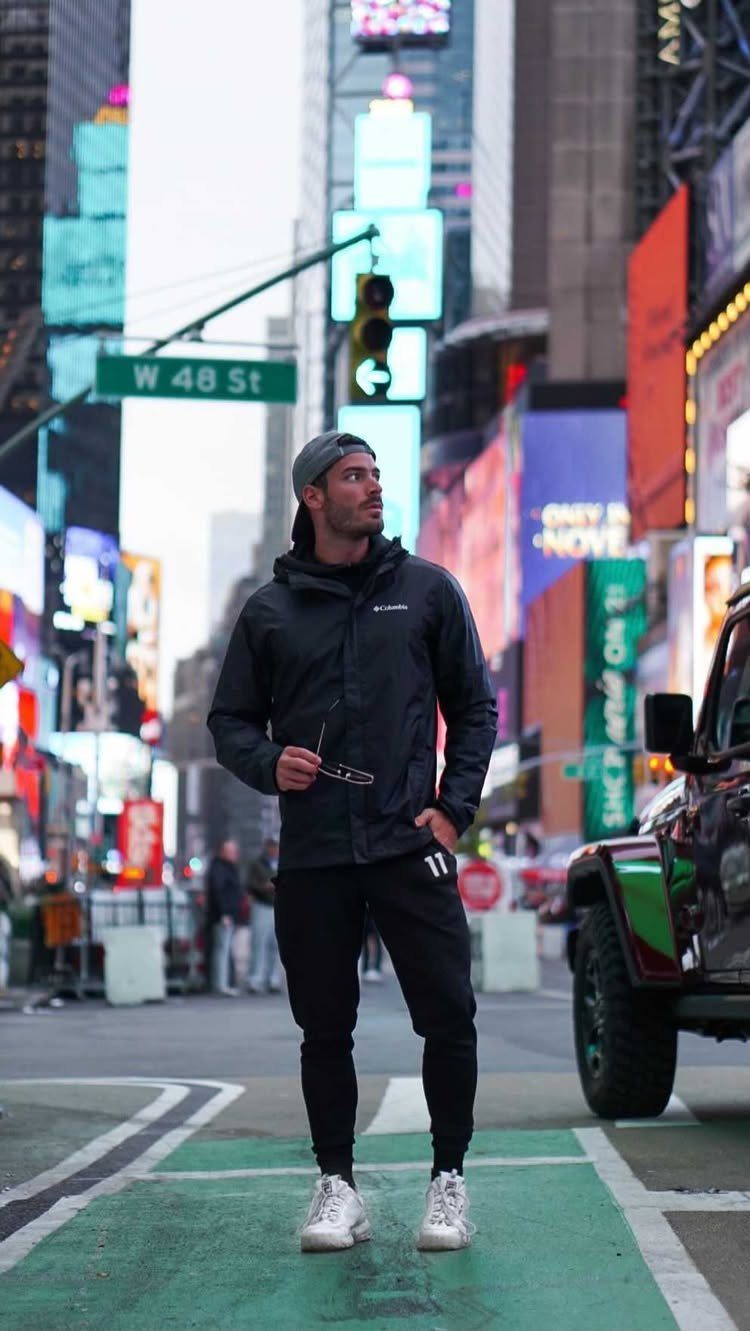 Man in black hooded jacket and joggers standing in New York City Times Square