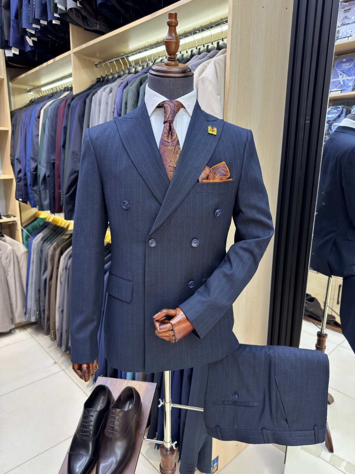 Navy blue double-breasted suit on a mannequin with brown leather dress shoes.