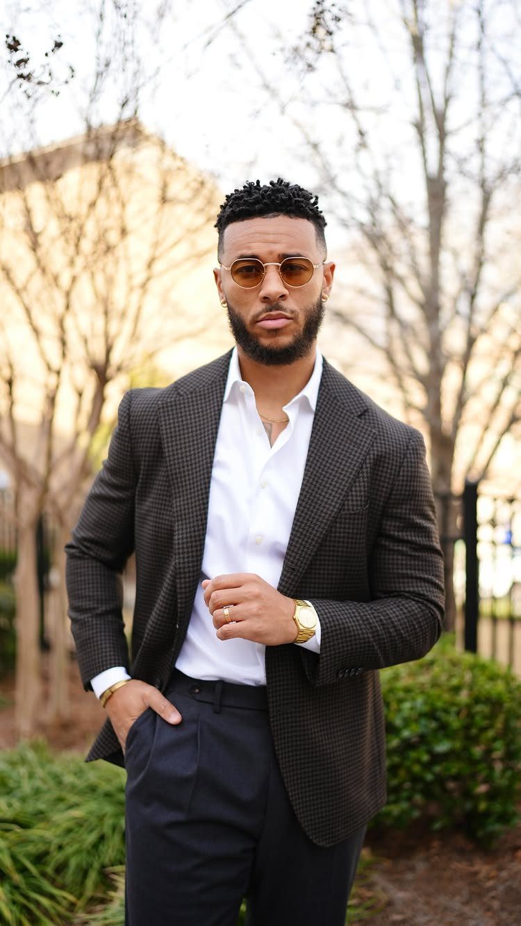 Man wearing a brown textured blazer, white shirt, and navy trousers outdoors.