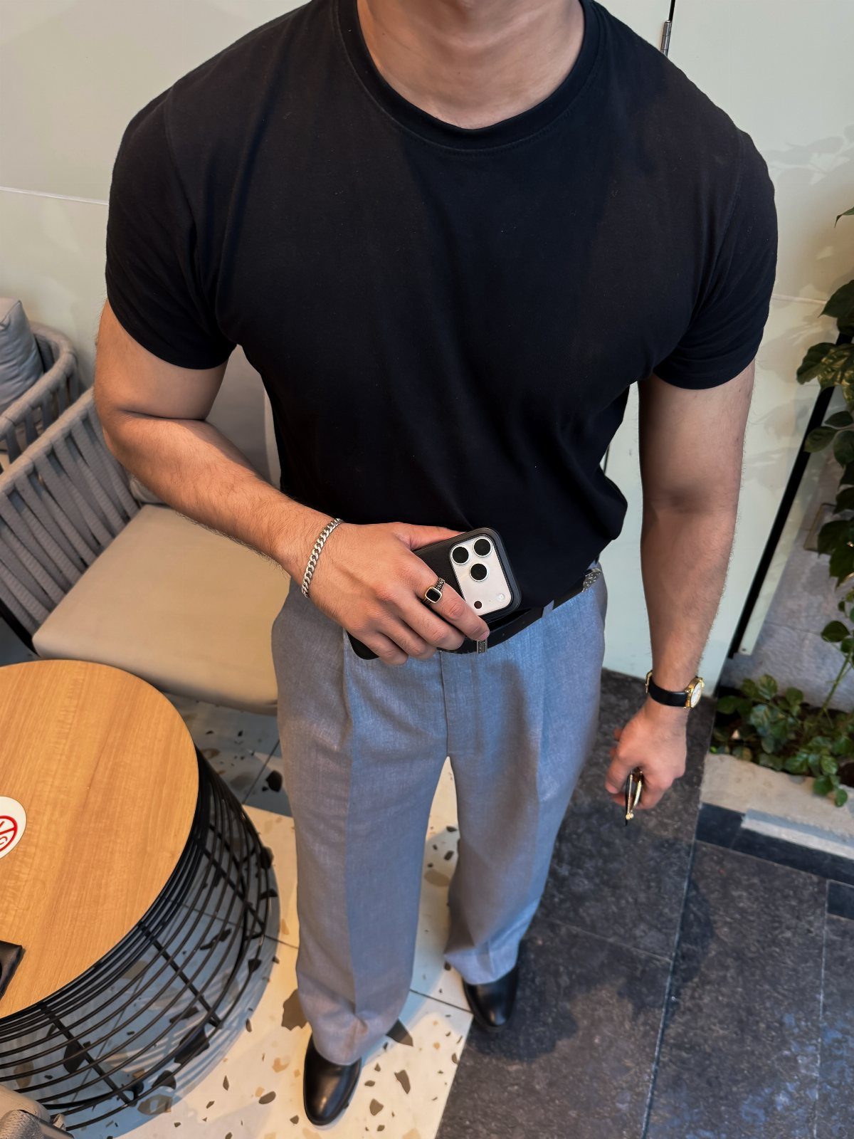 Man in a black t-shirt and grey trousers posing for a fashion photo.