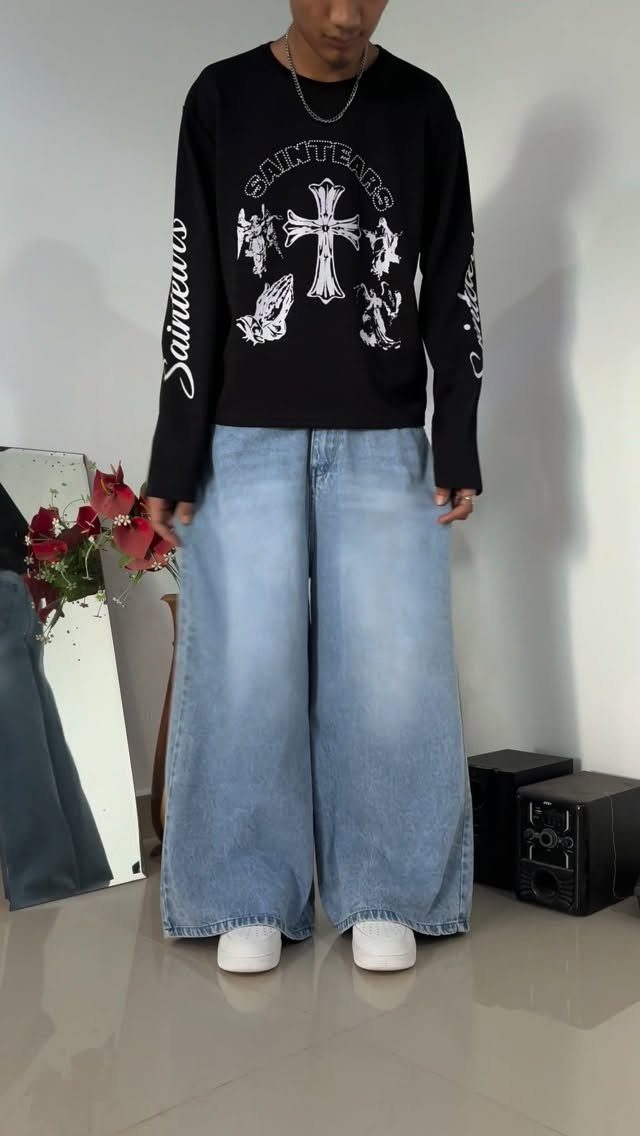 Person wearing a black graphic shirt and oversized light blue baggy jeans.