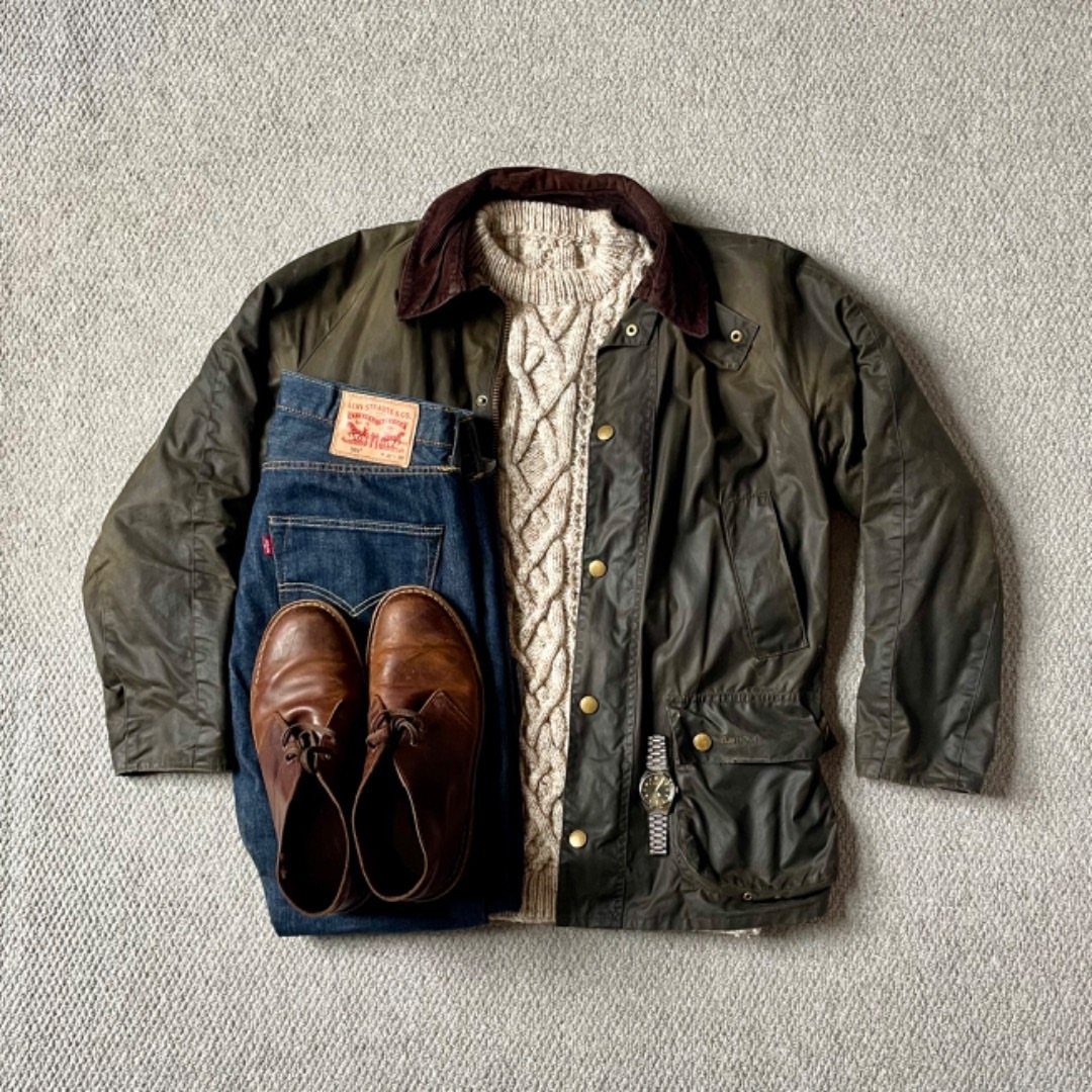 Brown suede chukka boots paired with blue jeans, cream sweater, and green jacket.