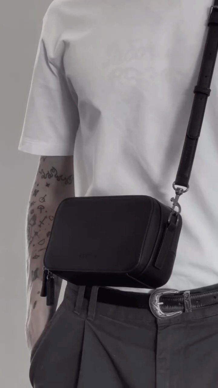 Men's Fashion Crossbody Bag: 6 Styles Worth Carrying 5 Black rectangular crossbody bag worn by a person in a white t-shirt.