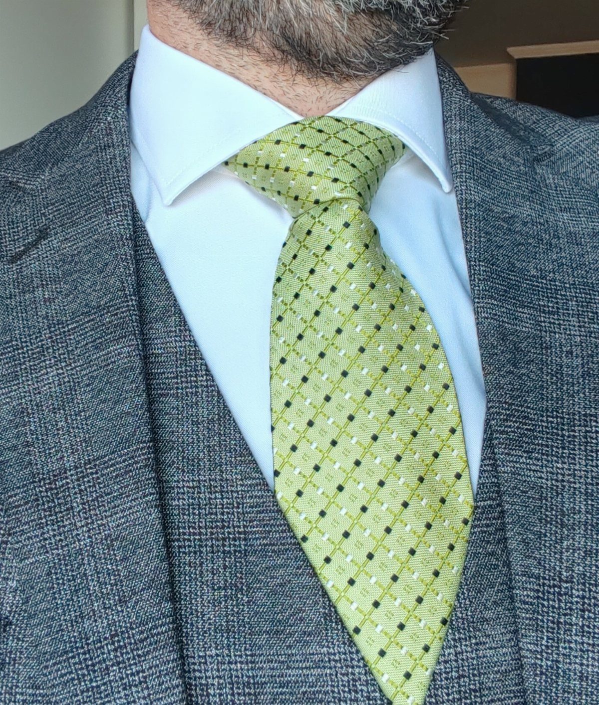 Man wearing a grey textured suit with a lime green patterned tie.