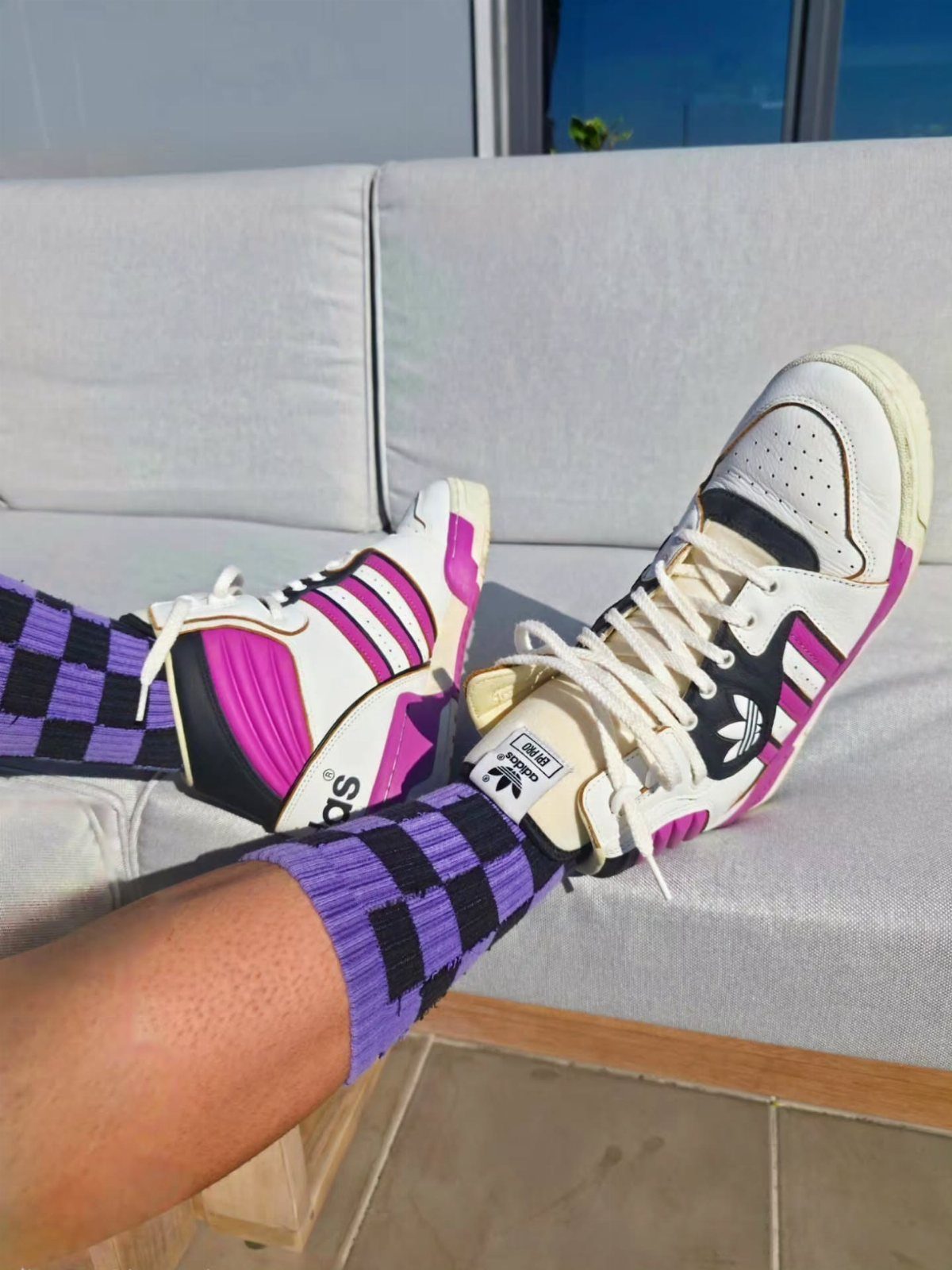 Adidas high-top sneakers in white, pink, and black with purple checkered socks.