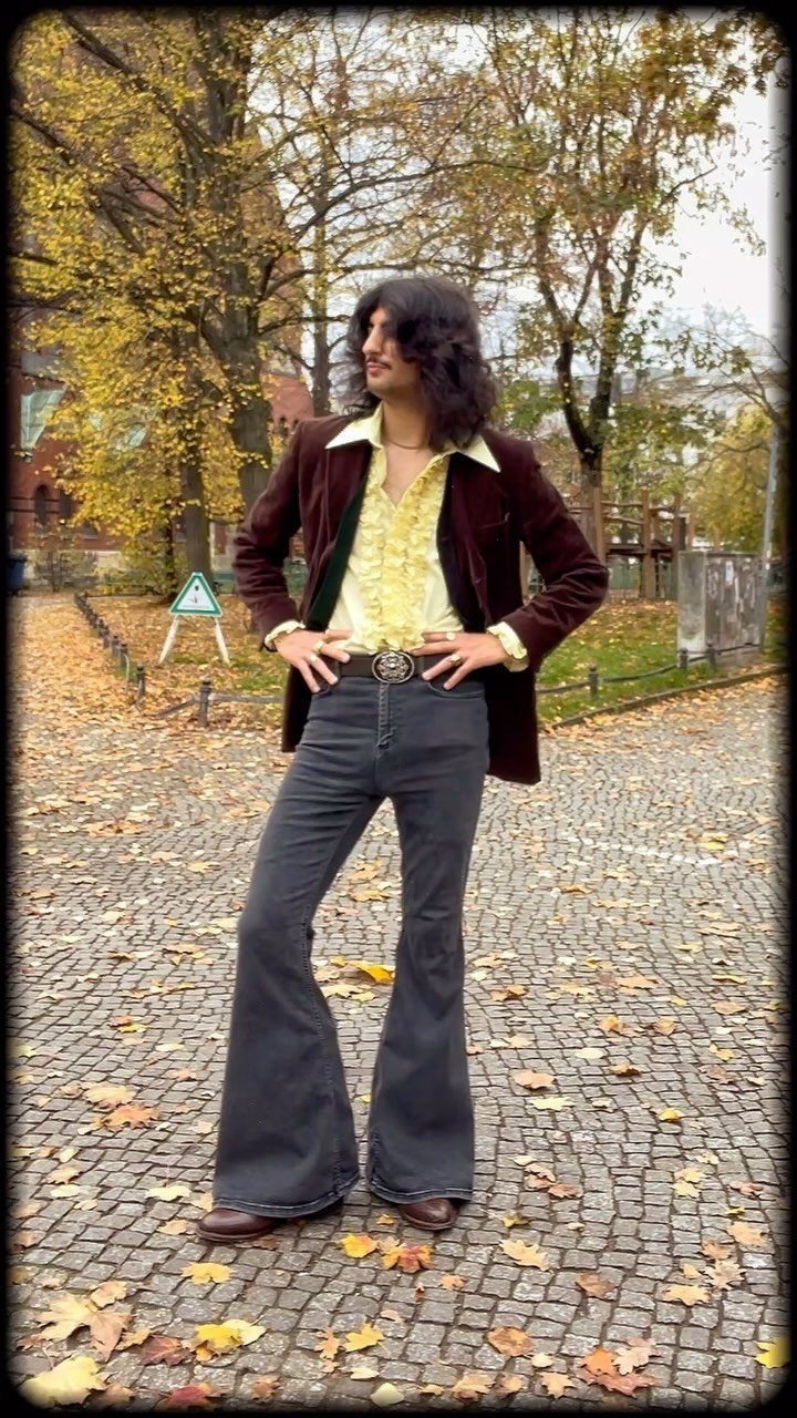 Man in 1960s style velvet blazer and wide-legged bell-bottom trousers on autumn path.